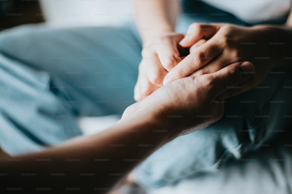 a person holding another persons hand on a bed