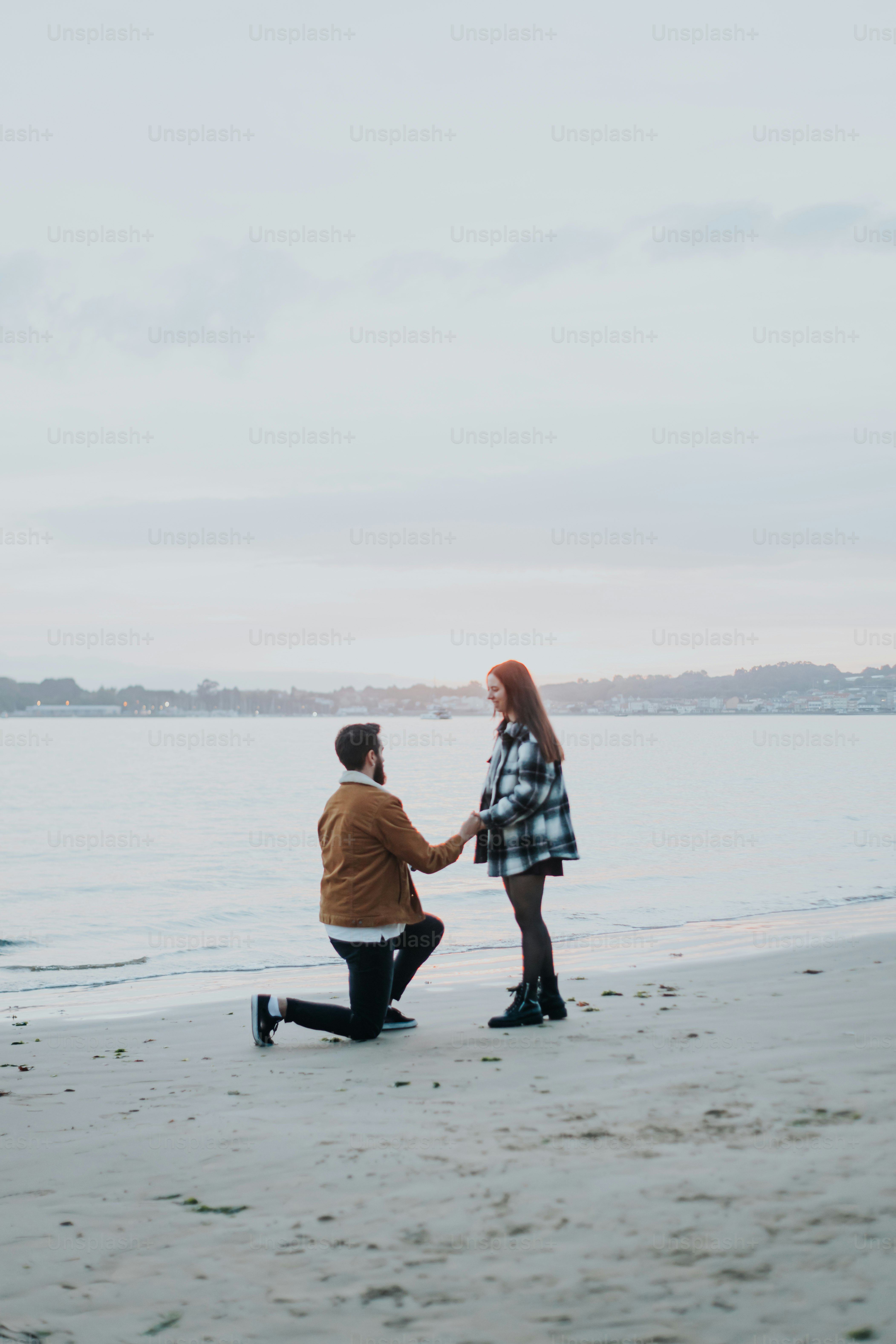 a man kneeling down next to a woman on a beach