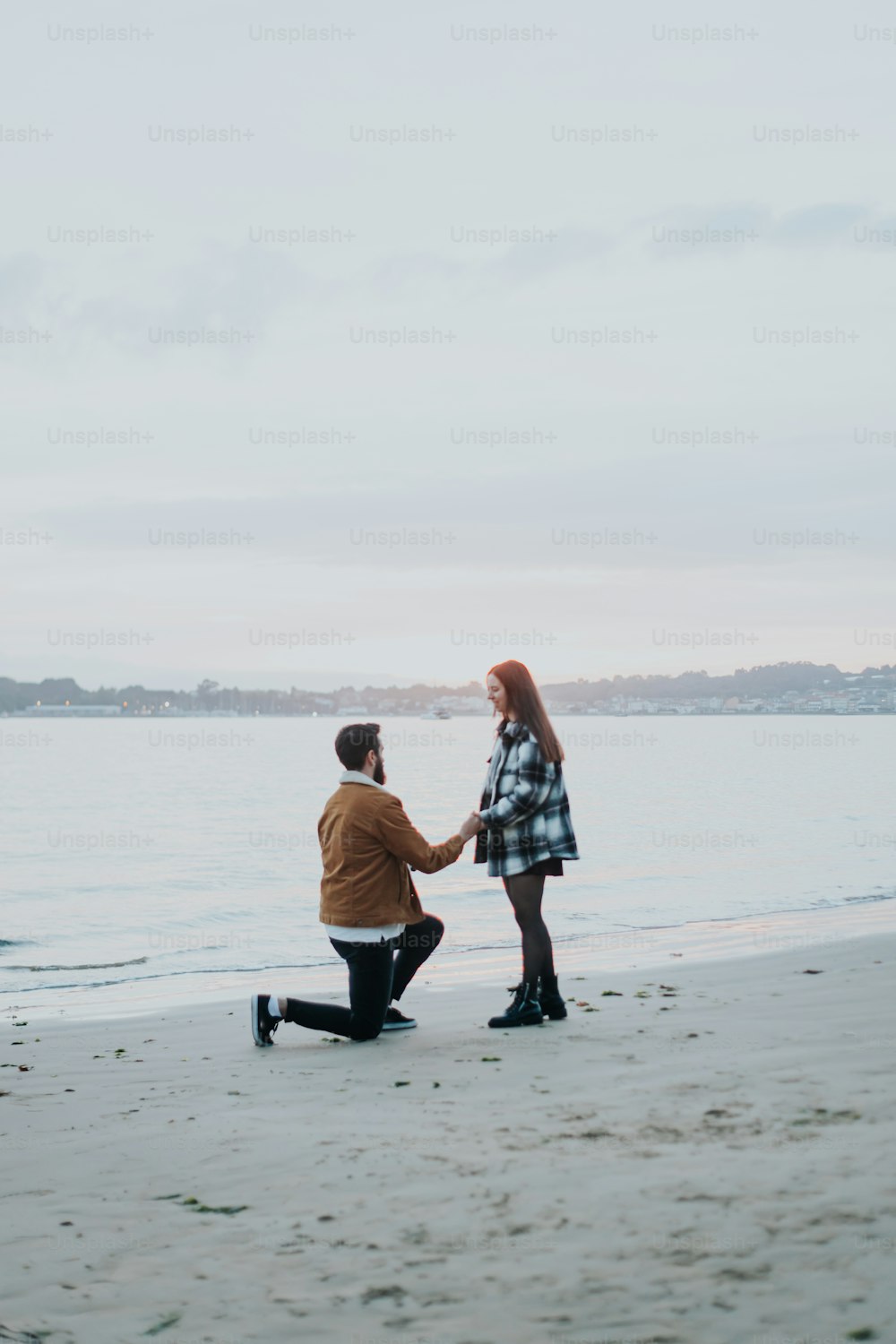 Un hombre arrodillado junto a una mujer en una playa