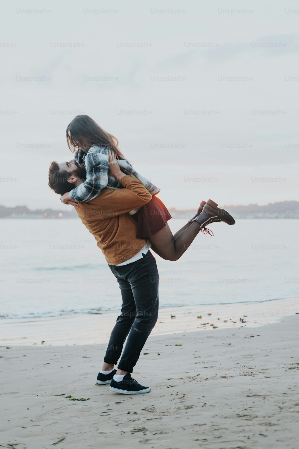 a man carrying a woman on his back on the beach