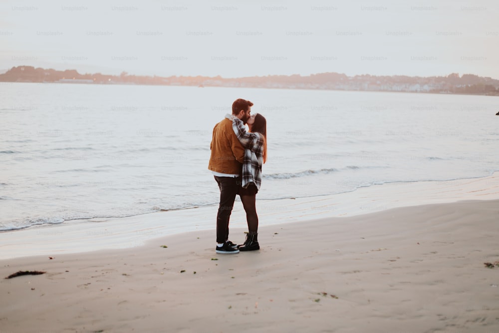 Un couple de personnes debout au sommet d’une plage de sable