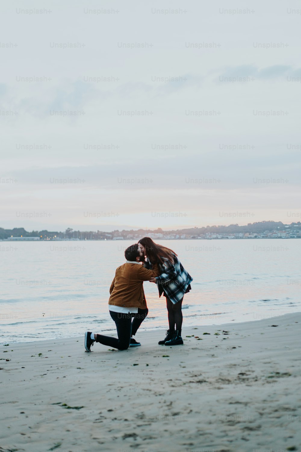 a man kneeling down next to a woman on a beach