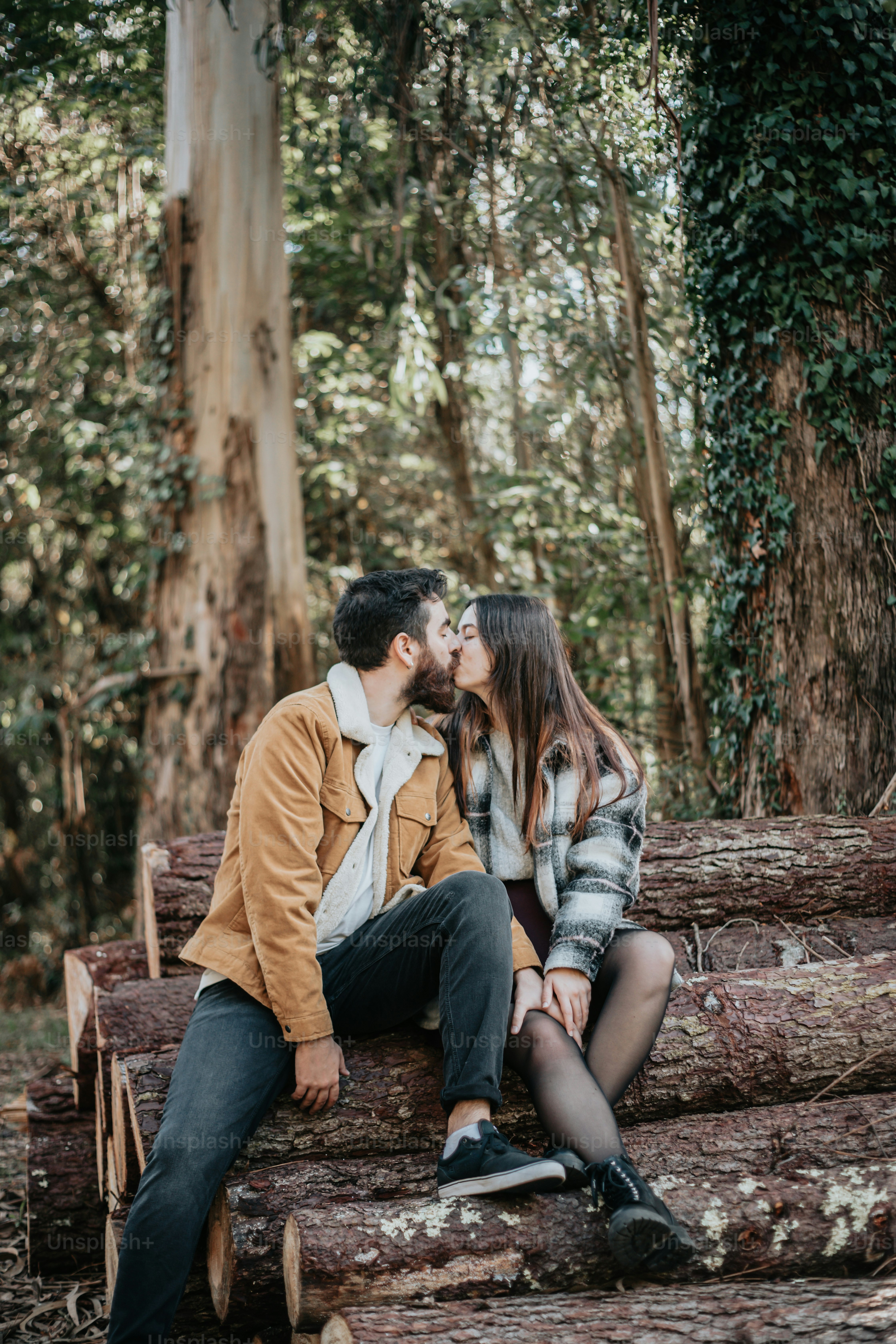 a man and woman sitting on a log in the woods