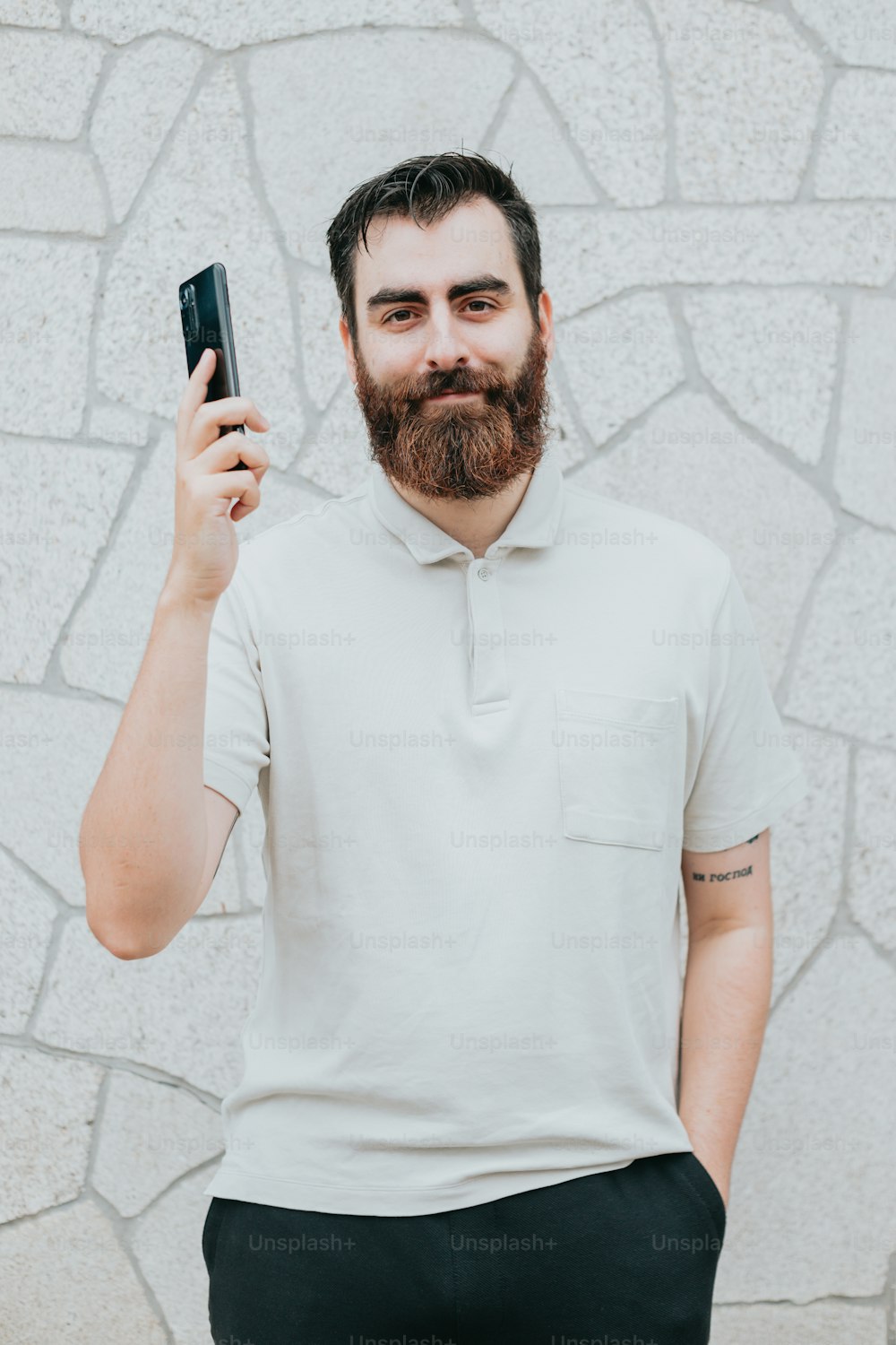Un homme avec une barbe tenant un téléphone portable