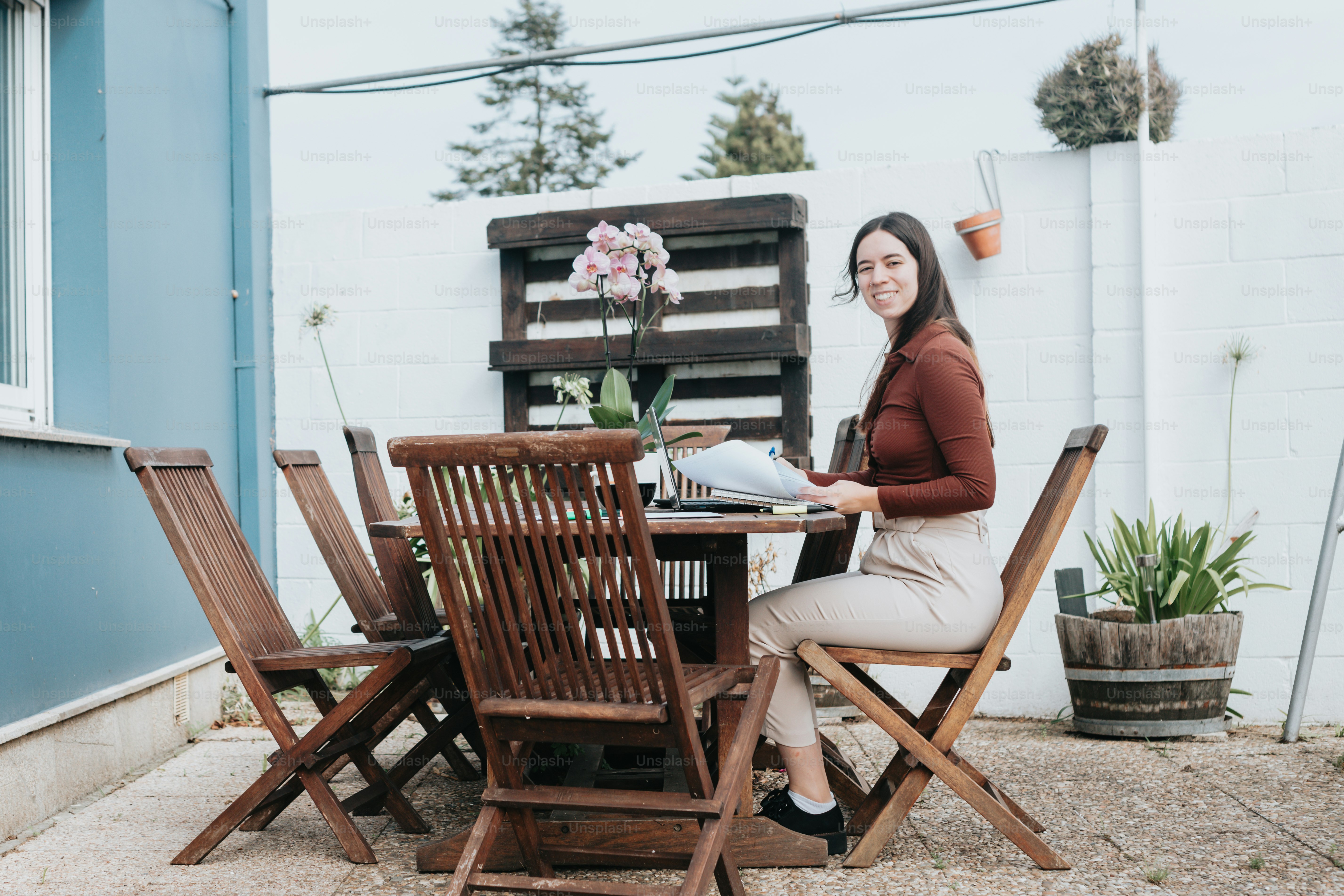 une femme assise à une table en bois à l’extérieur