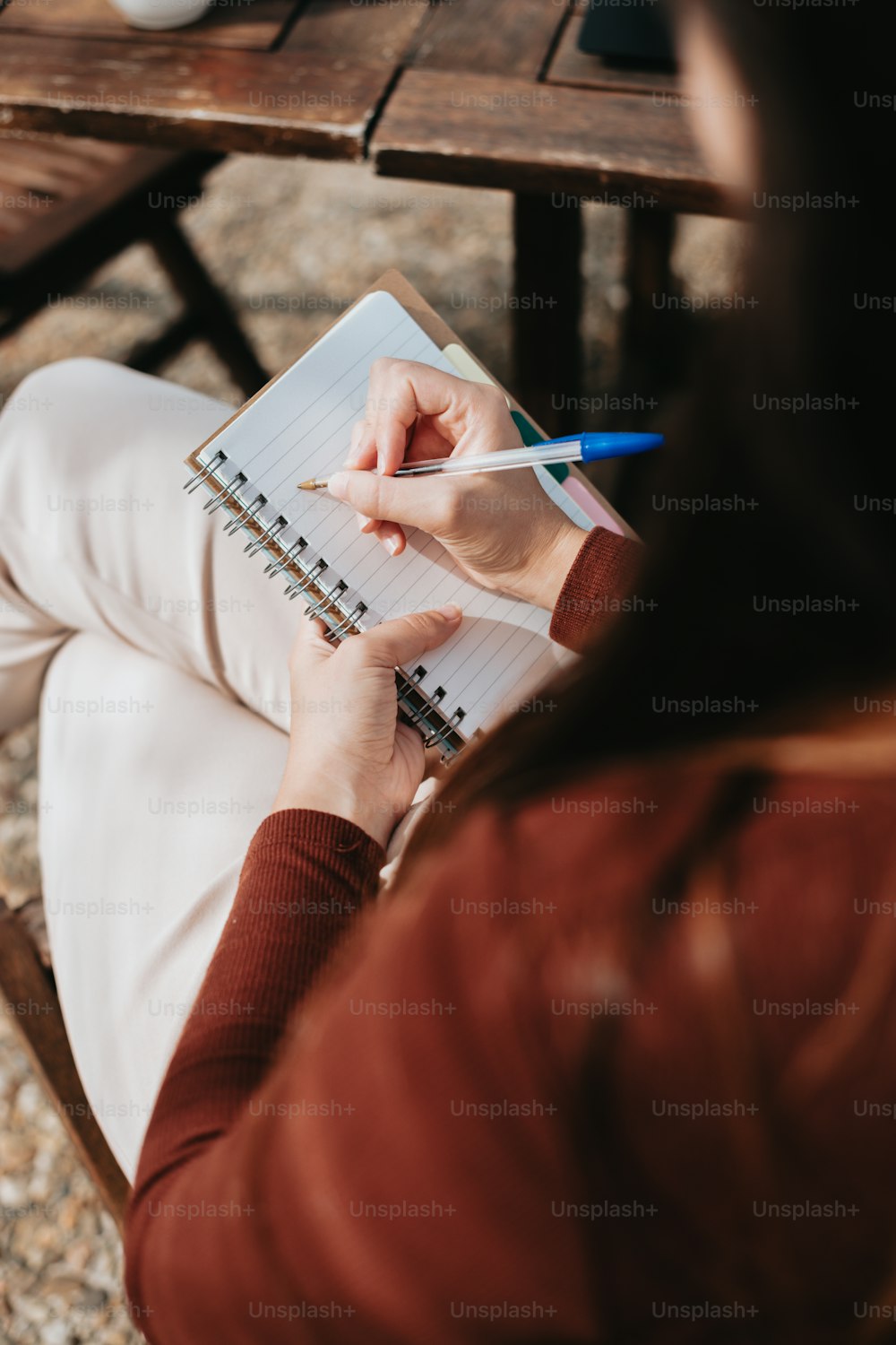 a woman sitting at a table writing on a notebook
