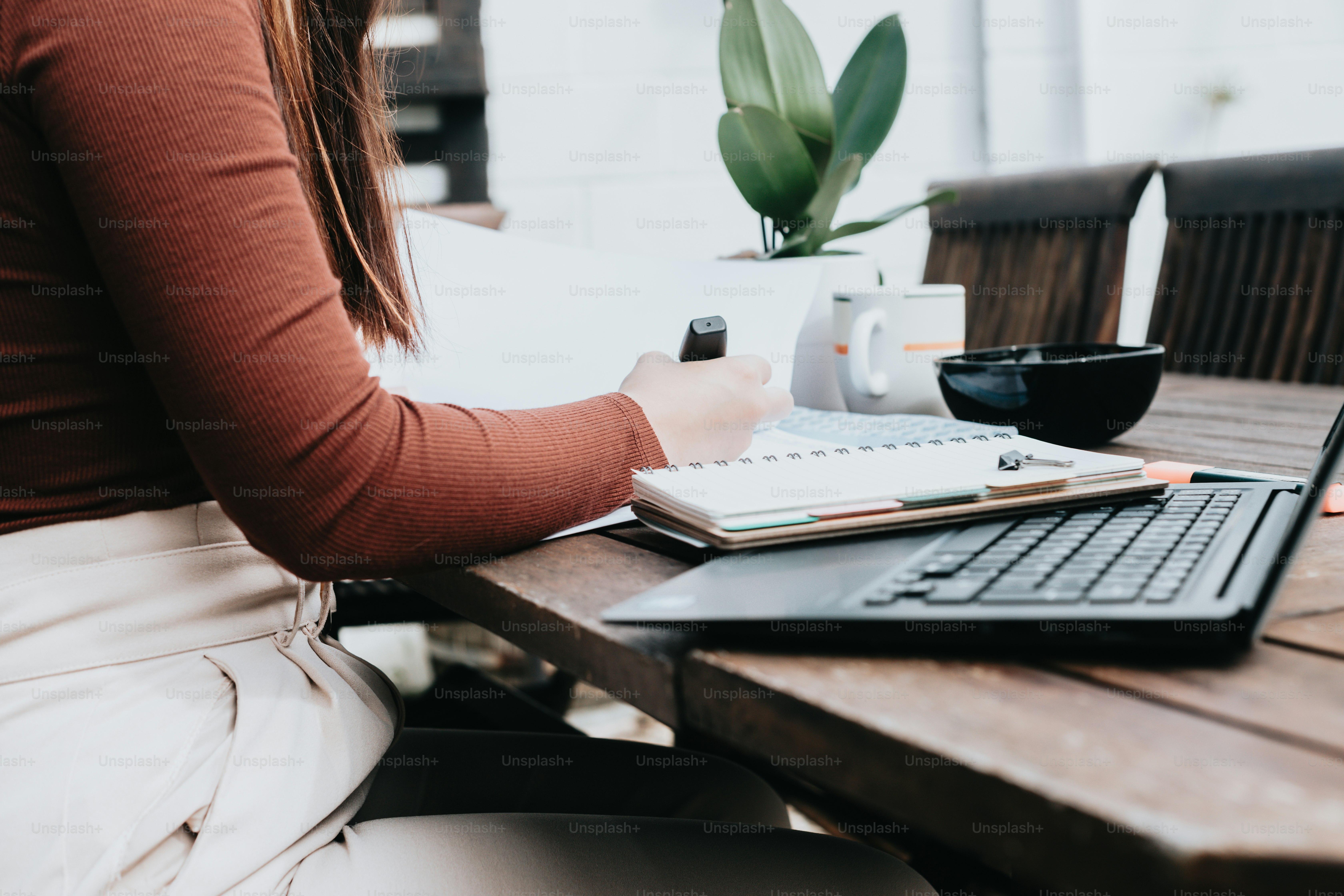 a woman sitting at a table with a laptop and a notebook