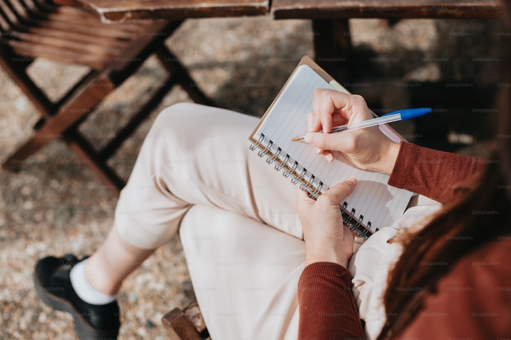 a woman sitting at a table writing on a notebook