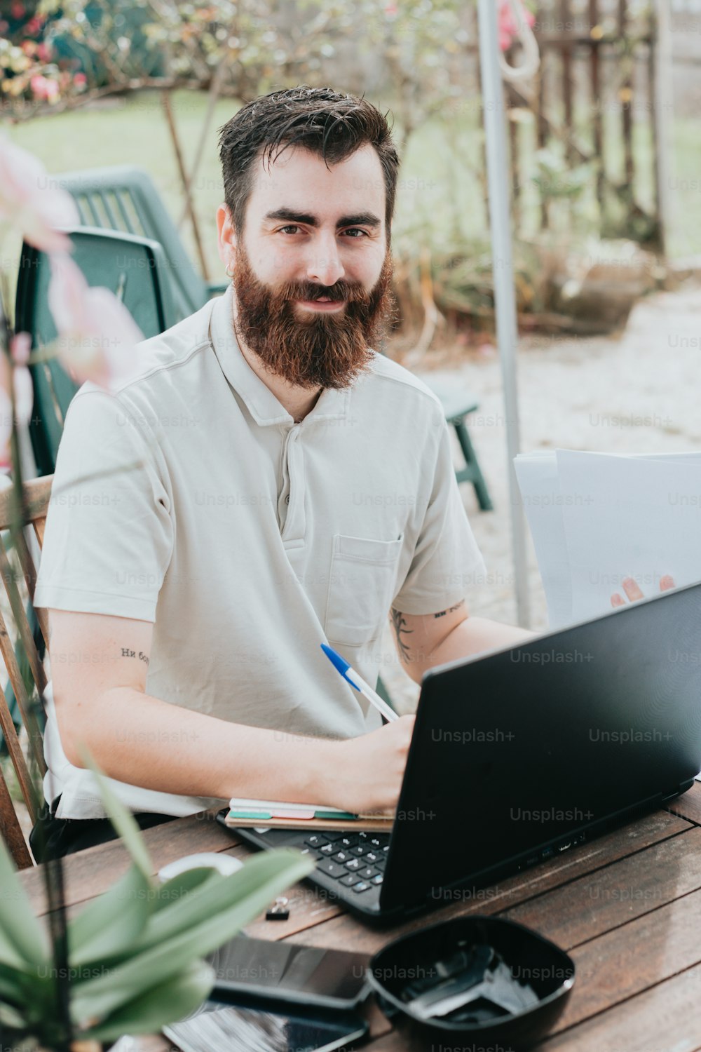 um homem com barba sentado em uma mesa com um laptop