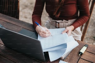 a woman sitting at a table with a laptop and papers