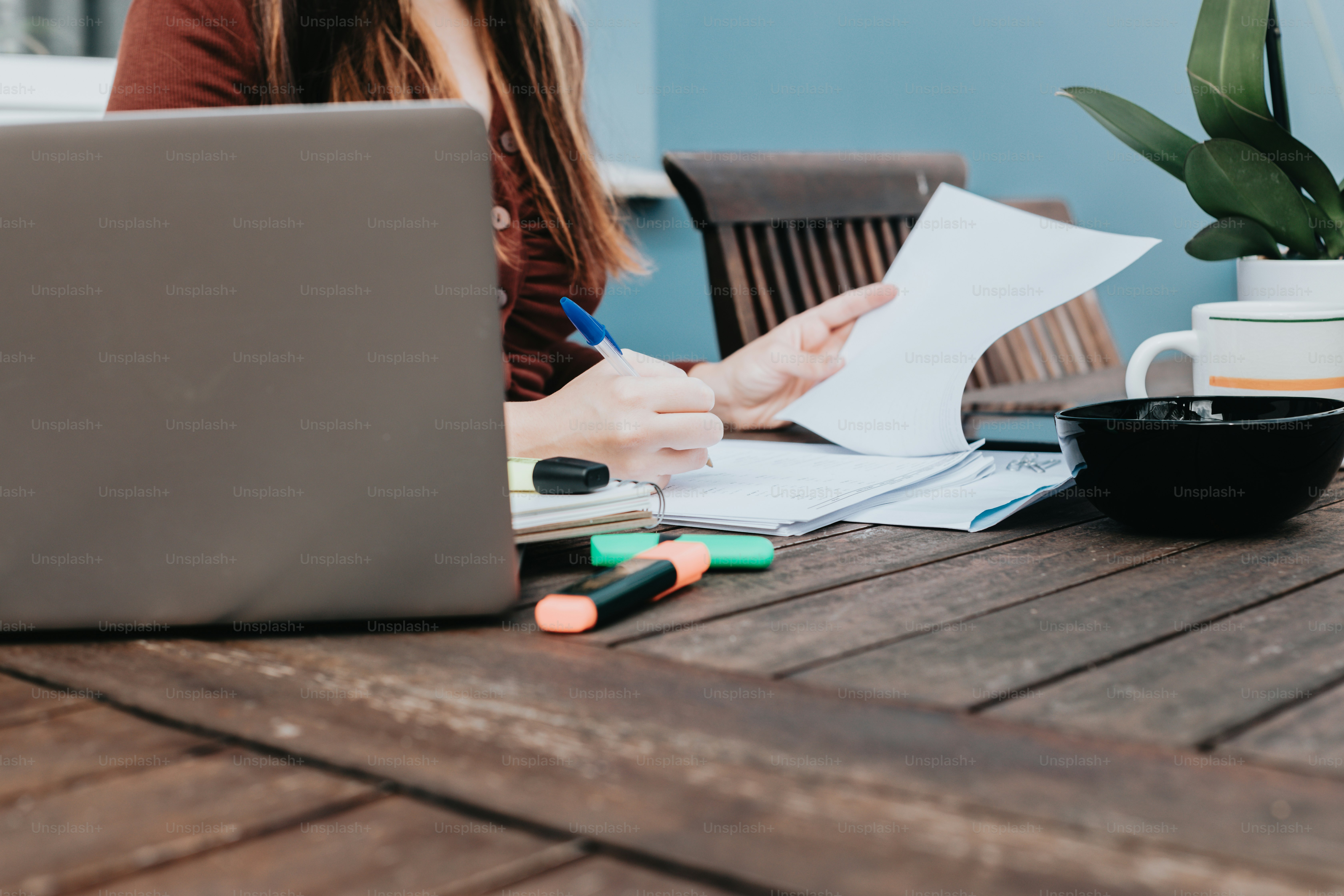 a woman sitting at a table with a laptop and papers