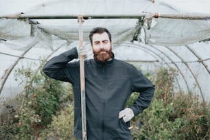 a man standing in a greenhouse holding a stick