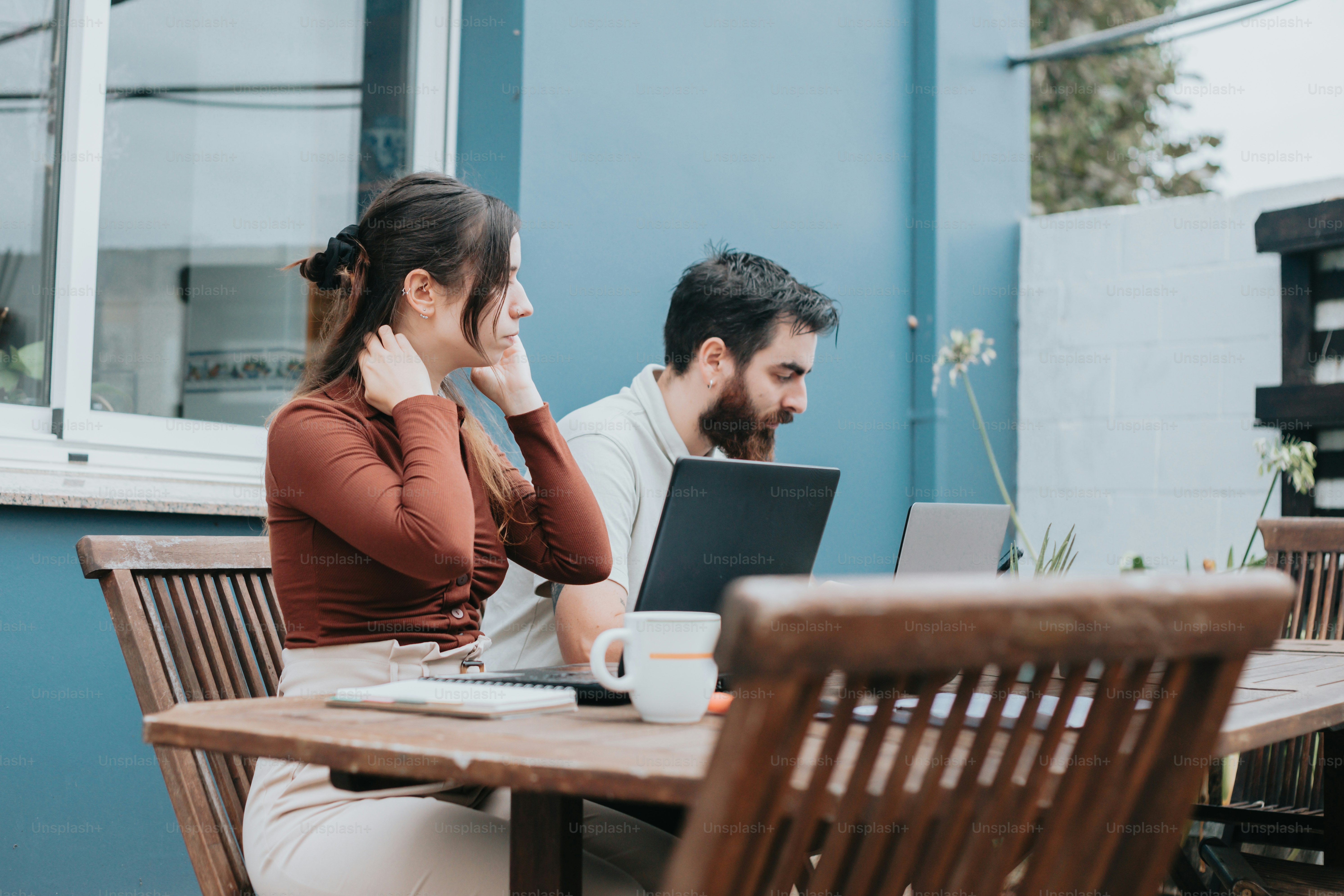 a man and a woman sitting at a table with laptops