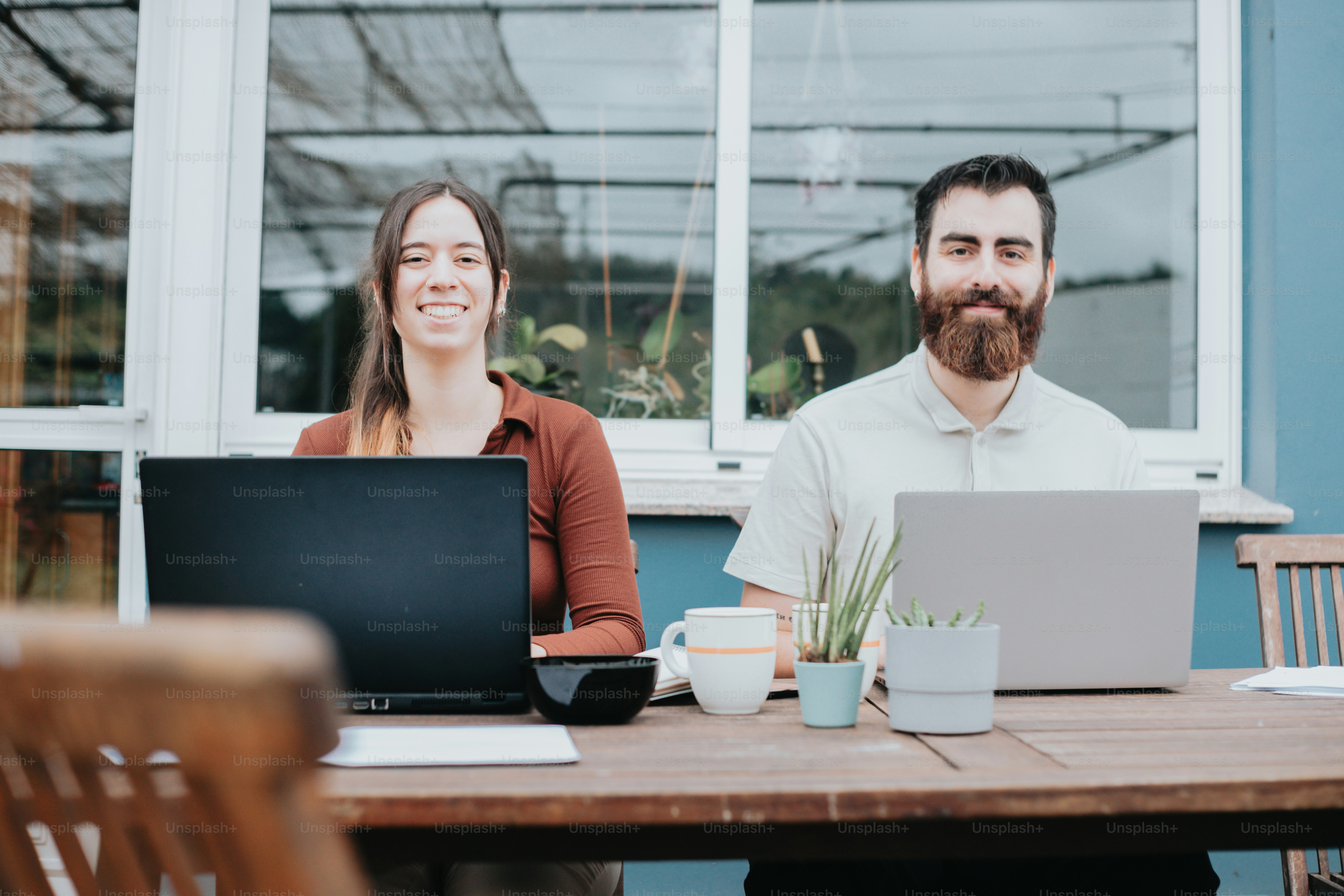 a man and a woman sitting at a table with laptops