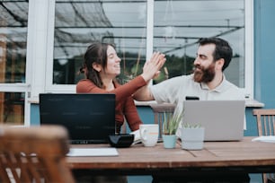 a man and woman sitting at a table with laptops