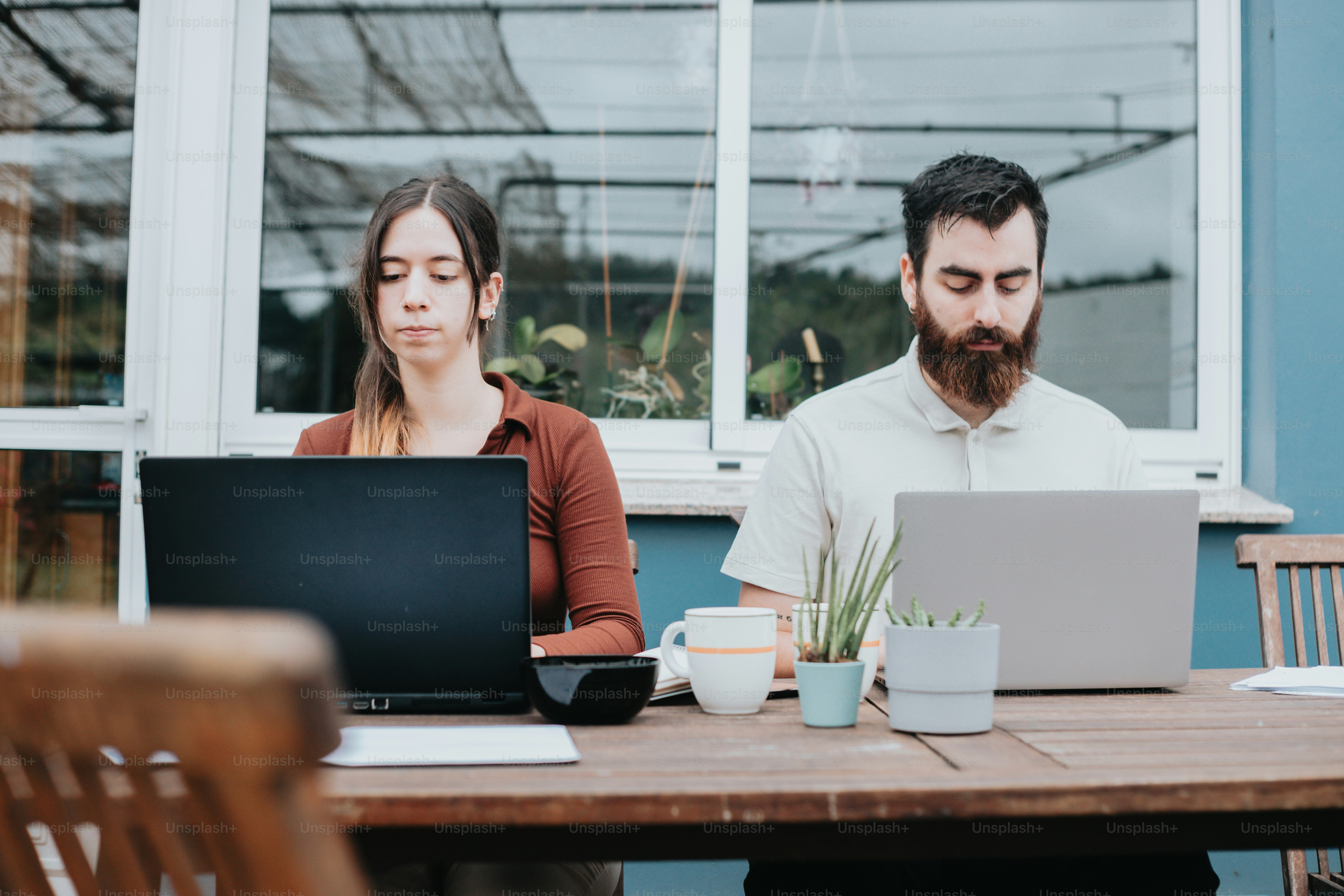 a man and a woman sitting at a table with laptops