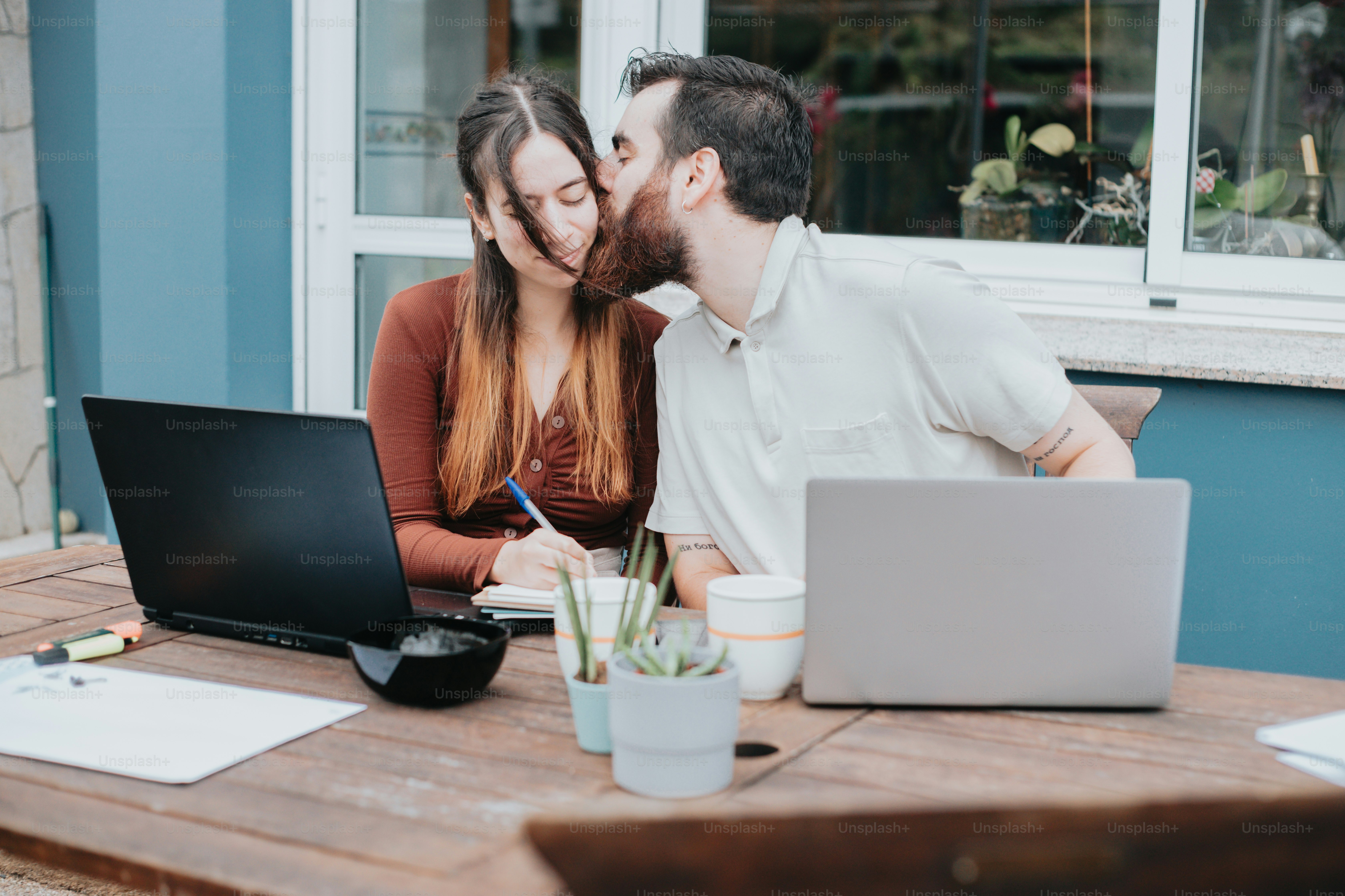 a man and a woman kissing in front of a laptop