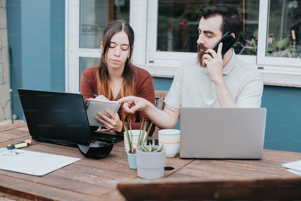 a man and a woman sitting at a table with laptops