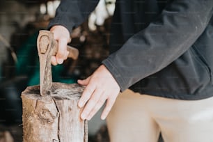 a person holding a hammer on top of a piece of wood