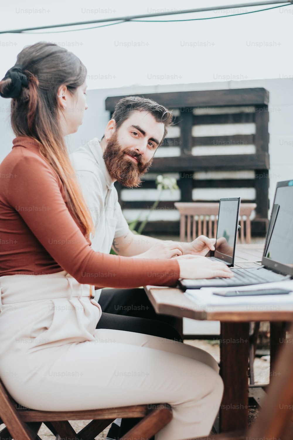 a man and a woman sitting at a table with laptops