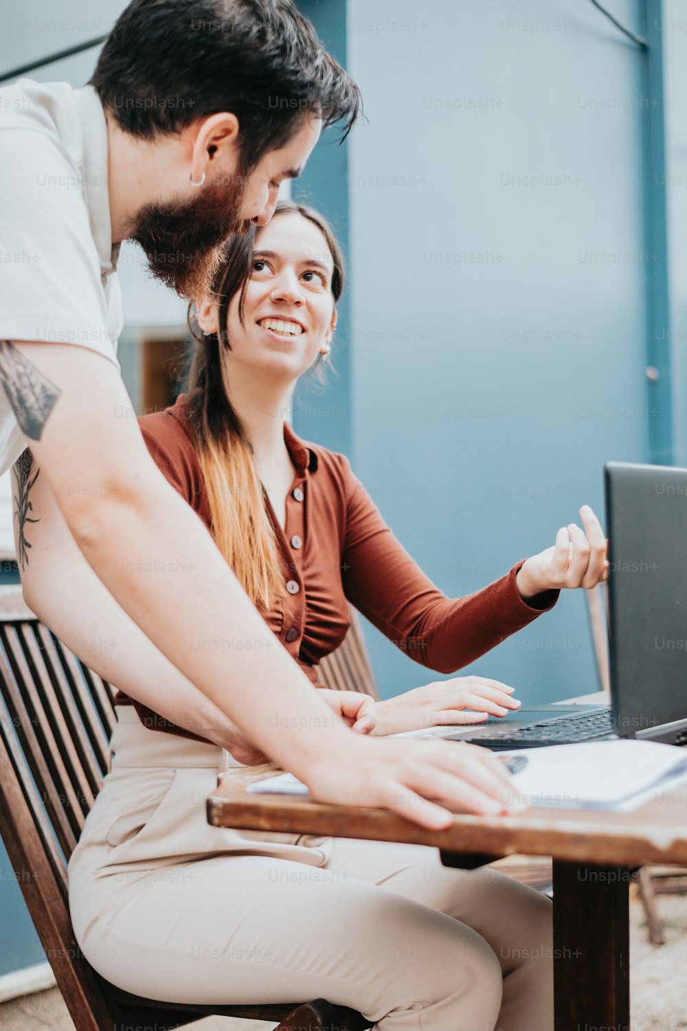 a man and a woman sitting at a table with a laptop