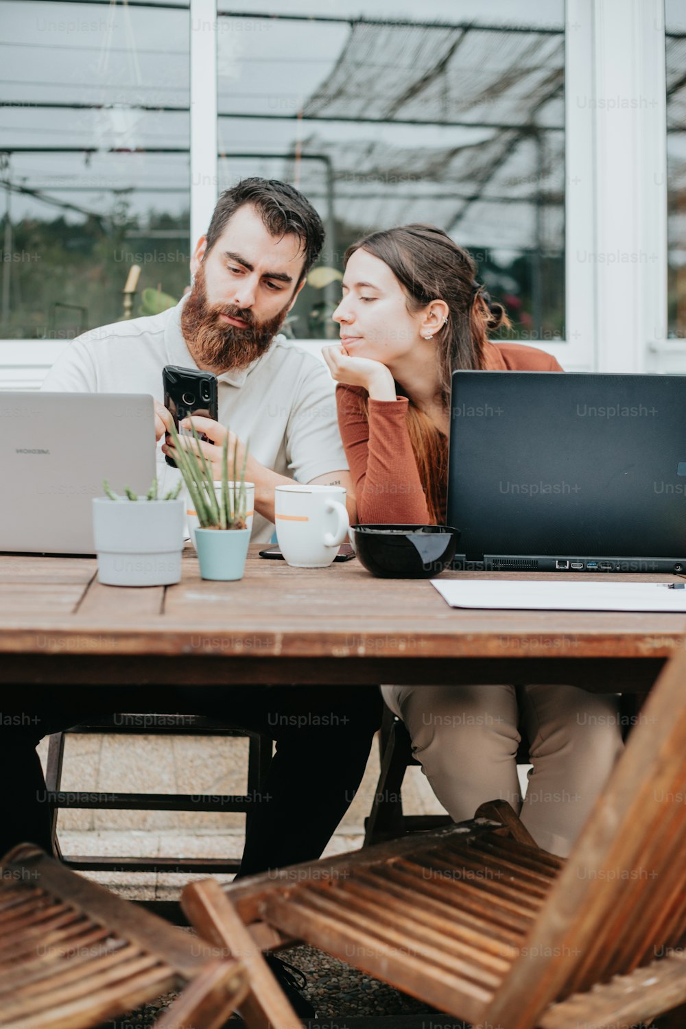 a man and woman sitting at a table looking at a laptop