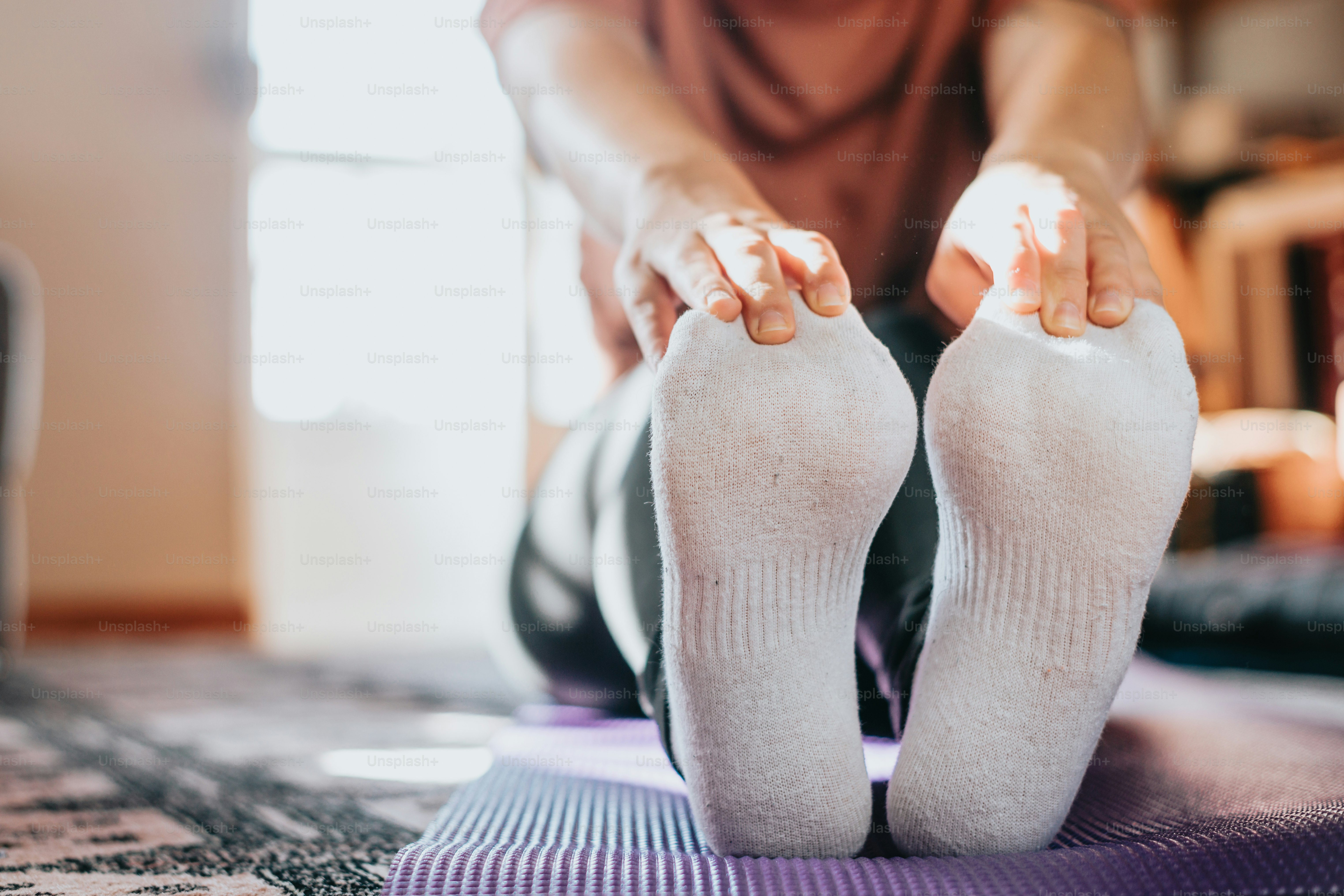 une personne assise sur un tapis de yoga avec les pieds levés
