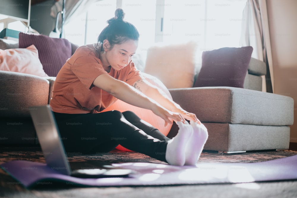 a woman sitting on the floor with her feet on a yoga mat