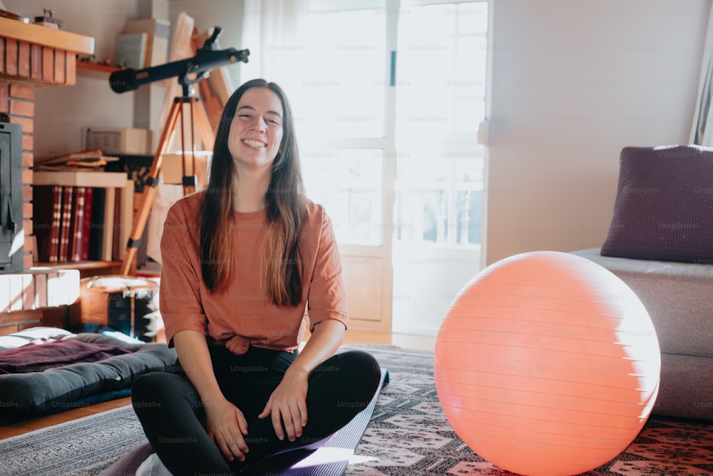 a woman sitting on the floor next to an exercise ball
