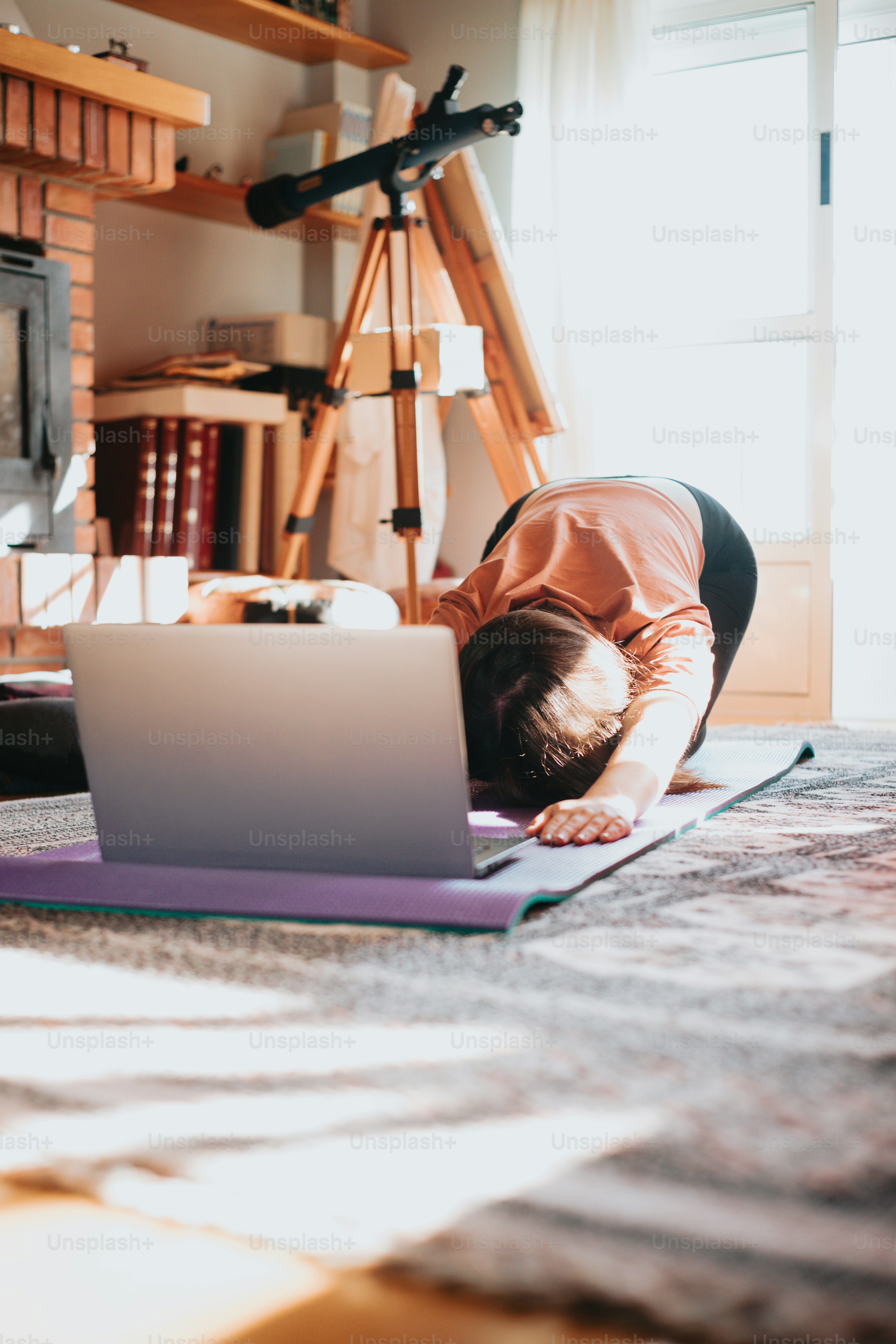 a person laying on a yoga mat using a laptop