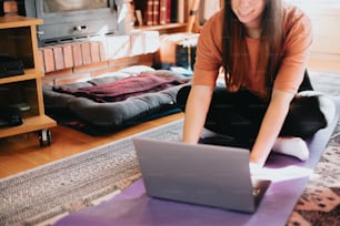 a woman sitting on the floor with a laptop