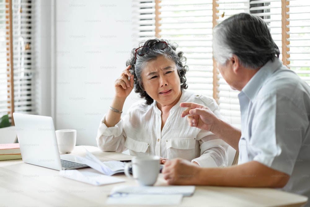 Senior mature man and woman having problem talk about family Financial crisis. Stressed old Asian Couple discussing and calculate budget, Debts, monthly expenses at home