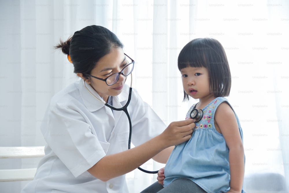 Jeune femme médecin asiatique examinant une petite fille avec un stéthoscope. Concept de médecine et de soins de santé.