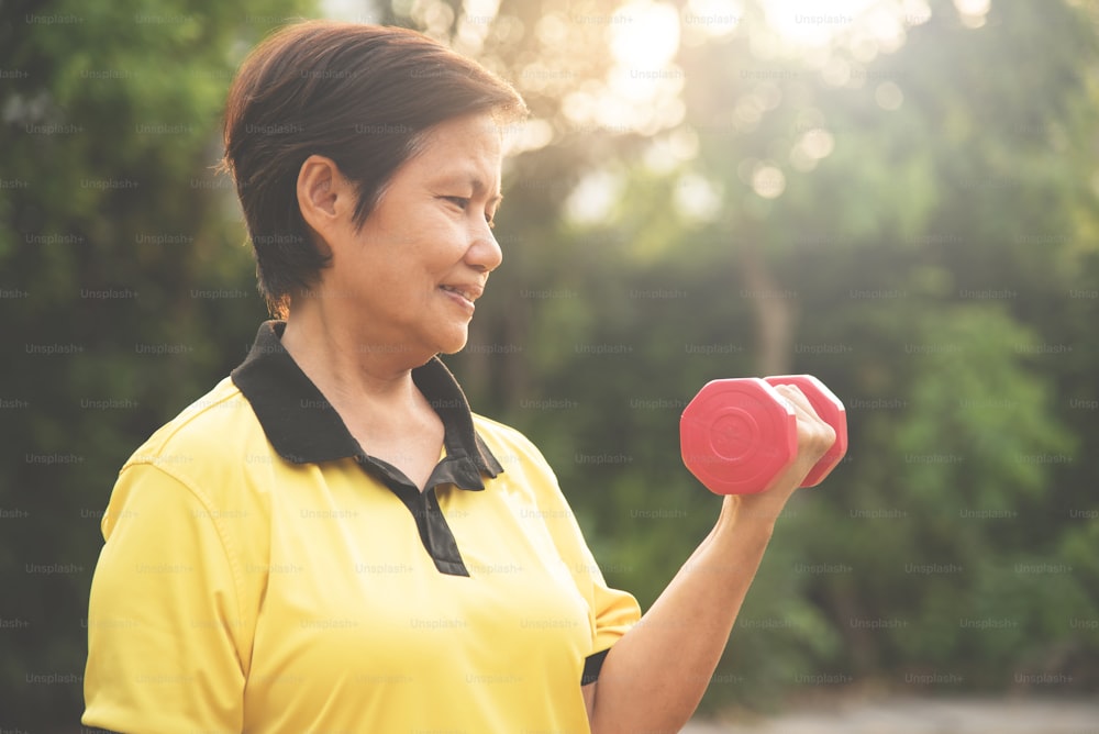 Asian Senior woman lifting dumbbell on natural background.