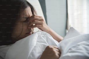 Mujer asiática resfriada. Chica con migraña en su cama. Enfermedad, concepto de enfermedad.