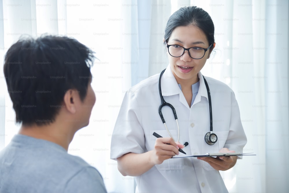 診察室で男性患者と一緒にチェックリスト用紙を診察し、メモするアジアの女性医師。
