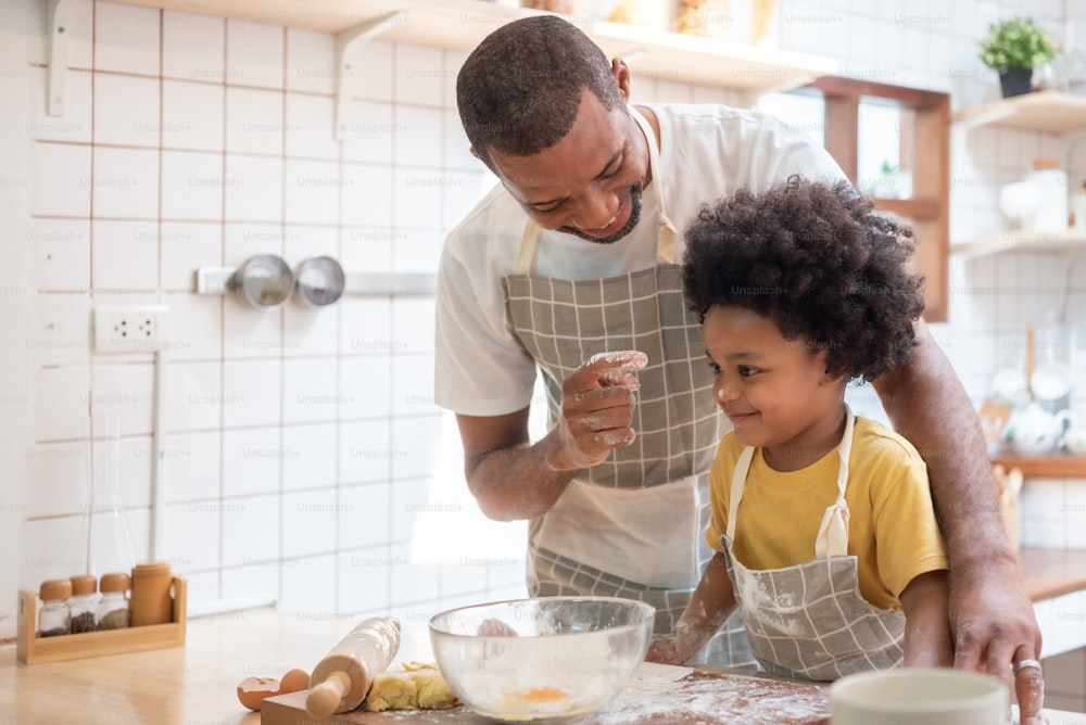 Black African American father enjoy playing with little son while baking cake or cookie in the kitchen, Family have fun cooking