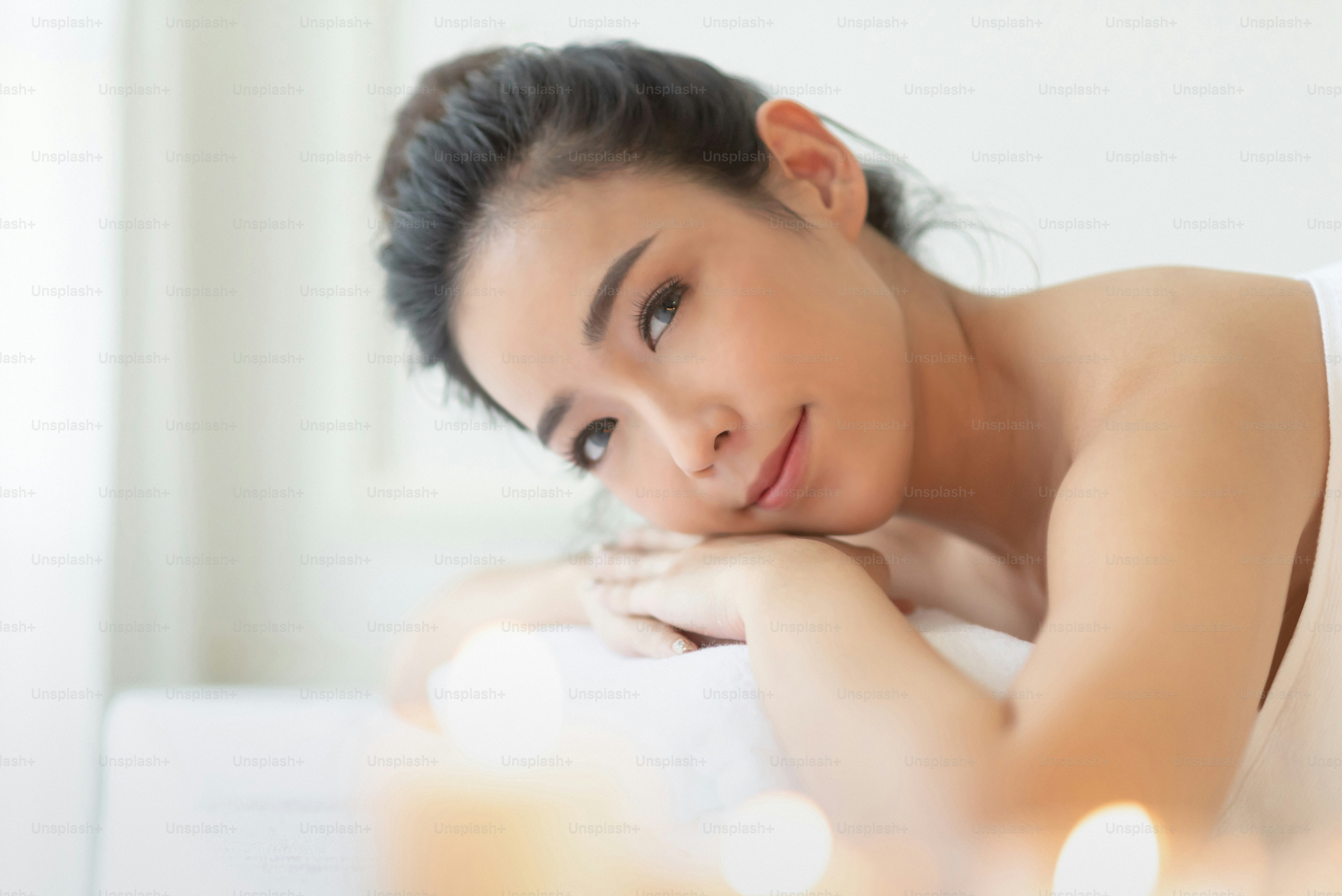 Portrait of Pretty Asian woman is relaxing in the white room at the spa salon. Enjoying, Smiling, Resting. Looking camera.