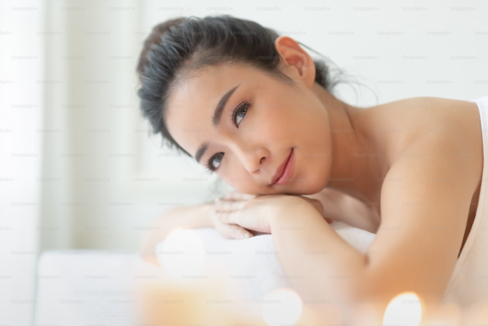 Retrato de una mujer asiática bonita se relaja en la habitación blanca del salón del spa. Disfrutando, sonriendo, descansando. Mirando a la cámara.