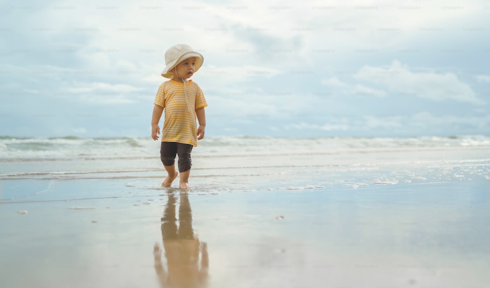 Retrato do menino asiático que caminha na praia, criança adorável feliz na natureza com mar bonito