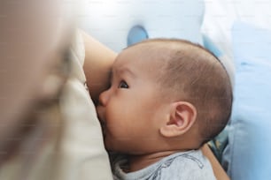 Primer plano de una madre asiática amamantando a su hijo recién nacido en casa. Mamá amamantando al bebé.