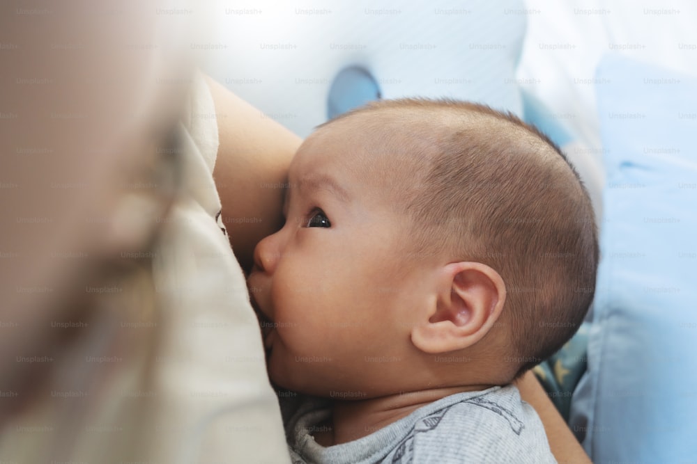 Madre asiatica ravvicinata che allatta al seno il suo bambino appena nato a casa. Mamma che allatta il bambino.