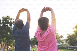 Asian senior couple stretching before exercise at park outdoor.