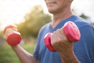 Happy Asian Senior man exercising with lifting dumbbell at park outdoor.
