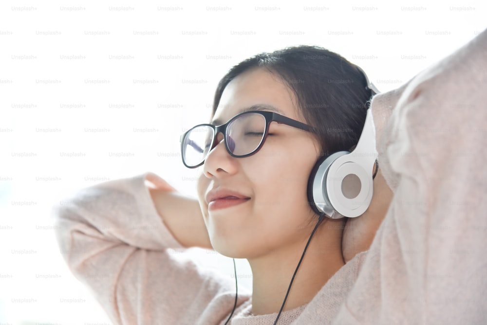 Feliz hermosa mujer asiática escuchando la música con auriculares 