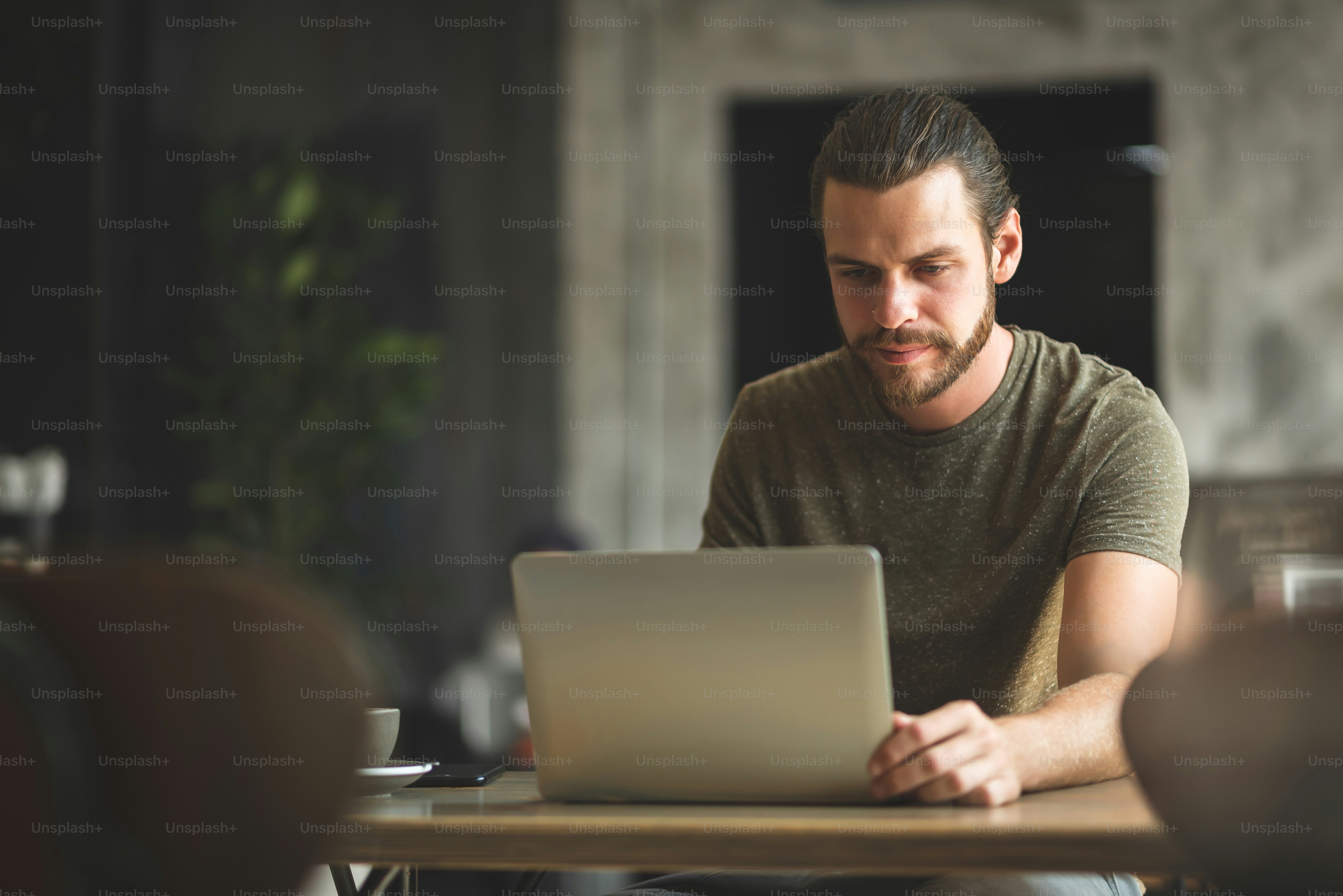 Bearded Male freelancer working on laptop computer at the coffee shop.