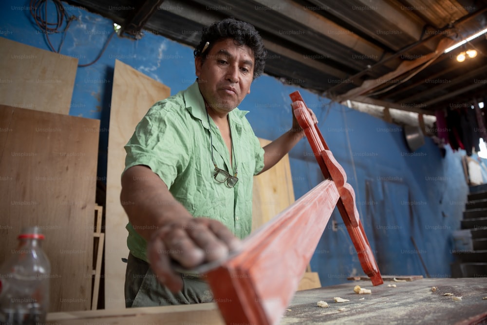 Mexican carpenter sanding a wood cross