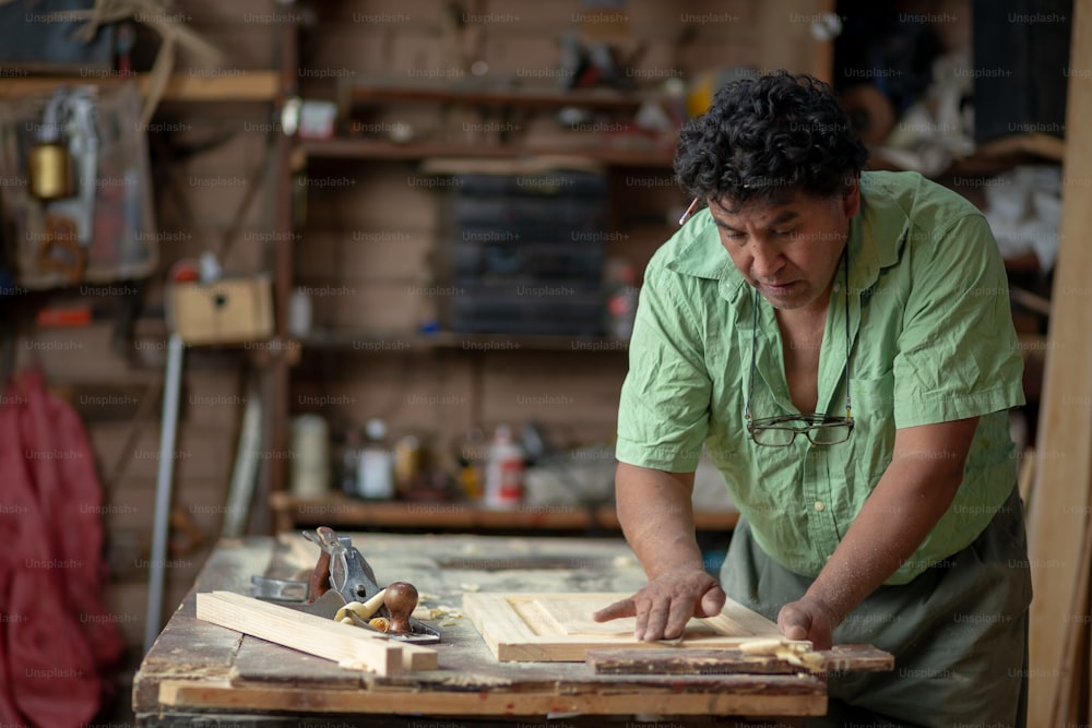 Carpintero mexicano trabajando en su taller lijando