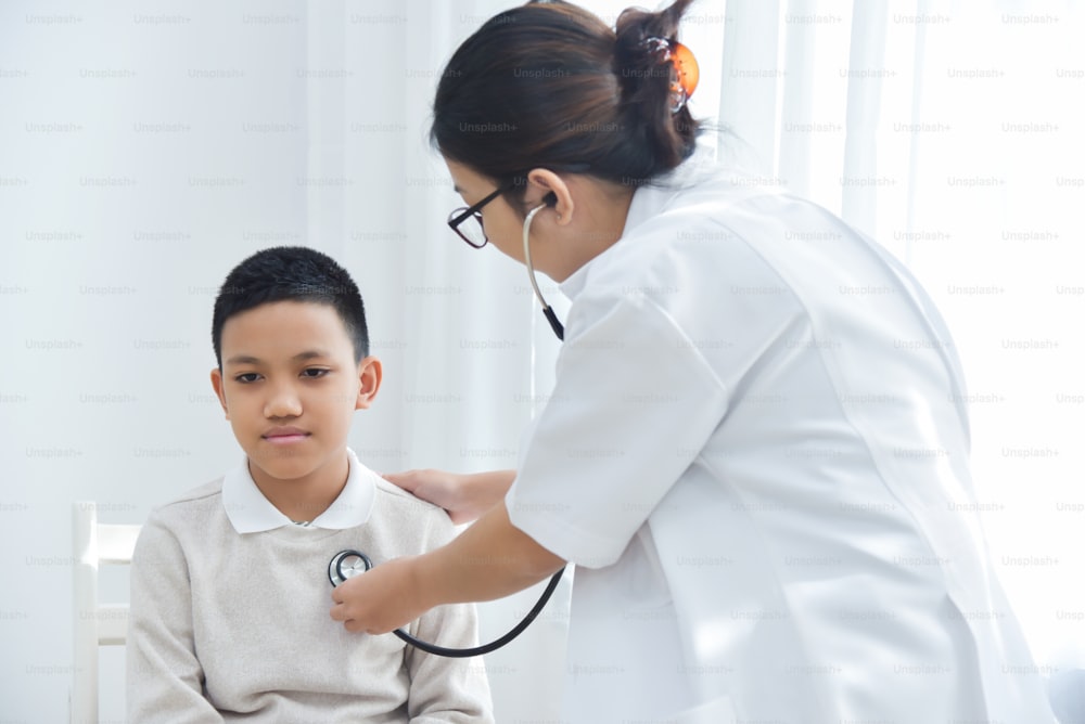 Joven doctora asiática examinando a un niño pequeño con estetoscopio. Concepto de medicina y cuidado de la salud.