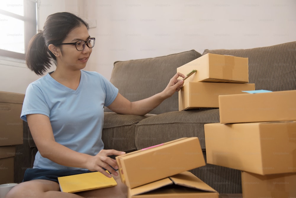 Jeune femme asiatique vérifiant des boîtes en carton dans son petit entrepôt. Entreprise propre